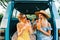 Two attractive cheerful women drinking lemonade near van, enjoying summer vibes in road trip