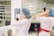 Two attractive dentist women preparing for work putting medical caps and looking at the mirror in the dental clinic.