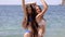 Two attractive girls in bikinis seductively moving while standing next to the sea