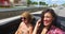 Two attractive girls driving in convertible with top down and enjoying the wind