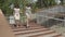 Two attractive girls wearing summer dresses running down the stairs in the city park. Carefree girlfriends having fun