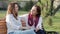 Two attractive happy old and middle-aged women girlfriends chatting in the park