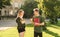 Two attractive students, female and male, having a conversation in the park near the university holding notebooks and coffee.