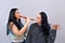 Two attractive teenager girls having fun with wooden flute  on light background