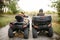 Two atv riders in helmets, back view, quad bike