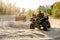 Two atv riders in helmets ride in a circle on sand