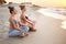 Two authentic women doing group yoga meditation on the beach at sunrise. Girls relaxing in lotus pose asana on sea shore
