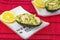 Two avocado salad with shrimps on the red background and white plates with lemon