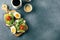 Two avocado toasts with cottage cheese, arugula, tomato on wooden board, cup of coffee. Top view