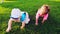 Two babies crawling on the bright green grass on a warm summer day