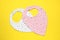 Two baby bibs on yellow background, top view. First food