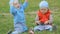 Two baby boys playing together on the lawn in the park
