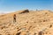 Two backpackers walking ascending mountain rock desert slope.