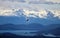 Two bald eagles soaring over trees with snow capped mountains in Alaska