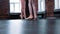 Two ballerina girls on training - putting on pointe shoes on the foreground and joining dancing to her friend on the