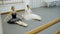 The two ballerinas do point toes sitting on the floor with feets together in the bright modern class.