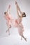 Two ballet dancers leaping in peach dresses in the studio