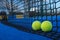 Two balls at the base of the net of a blue paddle tennis court