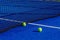 Two balls next to the net of a paddle tennis court. Racket sport concept