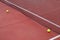 two balls next to the net of a red tennis court, racket sports concept