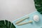 Two bamboo toothbrushes, tooth powder and a towel on a light gray concrete background.