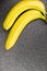 Two bananas joined together on a black plane. Exotic fruit, yellow bananas on a black stone surface. Bananas