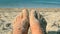 Two bare feet of caucasian woman soiled in sand shell rock on sandy sea shore