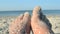 Two bare feet of caucasian woman soiled in sand shell rock on sandy sea shore