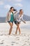 Two barefoot girlfriends laughing on the beach