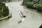 Two barges with a covered deck led by a tugboat on the Rhine river in west Germany, visible road and trees, aerial view.