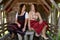 Two bavarian women in dirndl sitting by a wooden hut