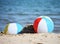 Two beach balls in sand on sea