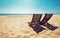 Two beach chairs on empty ocean beach under bright shining sun