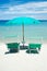 Two beach chairs with green umbrella.