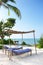 Two beach chairs with towels near pool. Lounge chairs with shelter under palm trees. Paradise hotel on coastline. Empty resort.