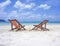 Two beach chairs on the white sand beach before blue sea