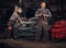 Two bearded auto mechanic in a uniform, repair a broken car in the garage.