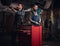 Two bearded auto mechanic in a uniform repair the car`s suspension while standing under lifting car in the repair garage