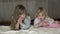 Two beautiful blonde little girls in bedtime in bed in the bedroom.