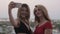 Two beautiful blondes in dresses making selfie on a mobile phone