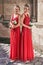 Two beautiful bridesmaids girls blonde and brunette ladies wearing elegant full length red chiffon bridesmaid dress with