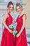 Two beautiful bridesmaids girls blonde and brunette ladies wearing elegant full length red chiffon bridesmaid dress with