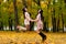 Two beautiful brunette girls jumping on background autumn park