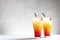 Two beautiful cocktails of tequila sunrise on a gray concrete background