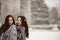 Two beautiful girlfriends hugging and smiling outdoors in winter. Two young female friends portrait closeup. Retouched, natural