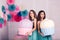 Two beautiful girls in blue dresses hold in their hands huge cakes in studio with decor of macaroons.