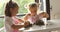 Two beautiful girls cooking cookies during morning light. family cooking, two kids learning by grandma mixing