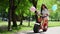 Two beautiful girls in denim shorts ride in the Park on an electric scooter in the summer