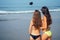 Two beautiful girls make a photo on the selfie-stick on the beach view from the back