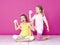 Two beautiful girls playing with homemade slime and having a lot of fun in front of pink background